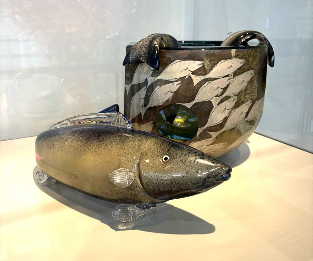 glass fish in front of a bowl with 2 fish tails flopping out