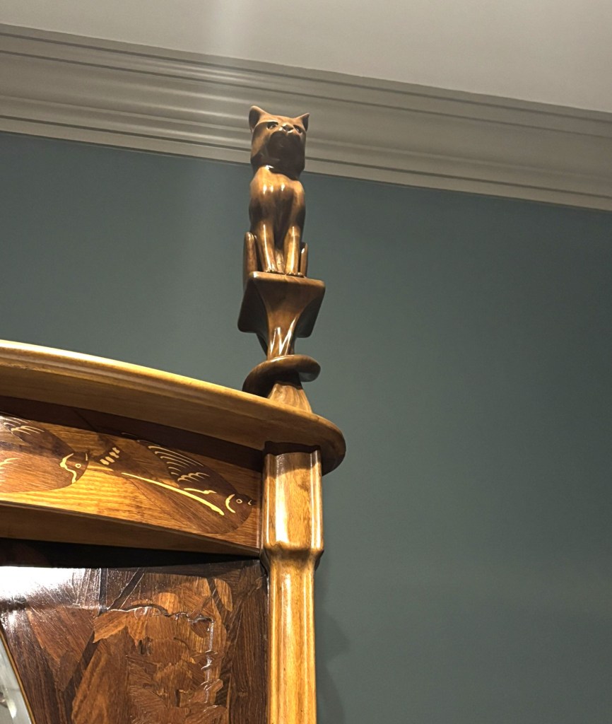 A wooden cat sitting on a pedestal.